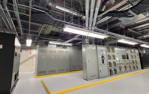 Electrical switchgear, UPS and CRAH units on concrete housekeeping pad. Overhead conduit, cable tray and  DC cabling