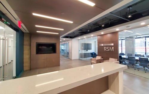 Neutral earthy tones, natural light, and corporate branding contribute to the relaxed feel of this spacious reception area adjacent flexible meeting room