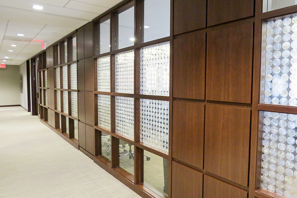 The custom office fronts blend a gridded wood panels, fritted opaque, and transparent glass panels that provide privacy while permitting natural light to penetrate to the interior spaces.  